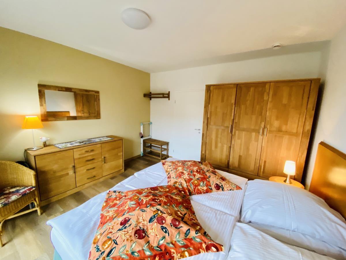 Doppelbett mit gemusterten Kissen, Holzfußboden und Glastür zum Balkon.