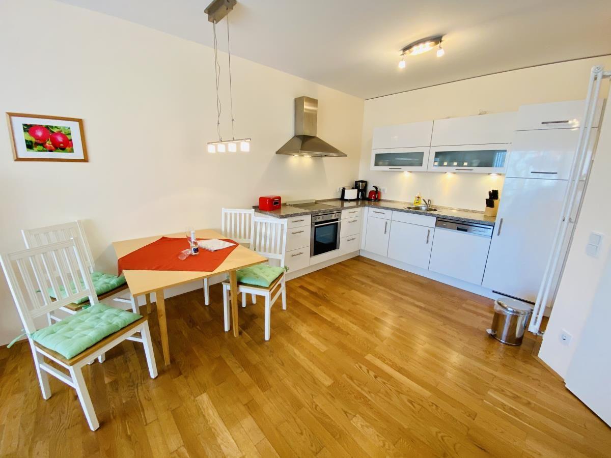 Haus mit Küche, Flur und Bad. Holzboden und weiße Möbel.