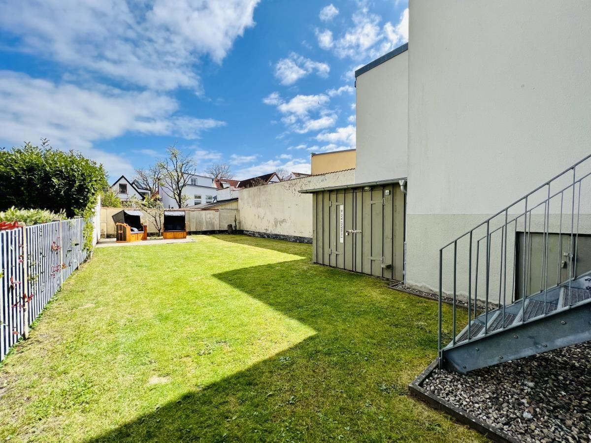 Parkhaus mit Glasfassade und Parkplatzschild. Straße und Grünflächen im Hintergrund.