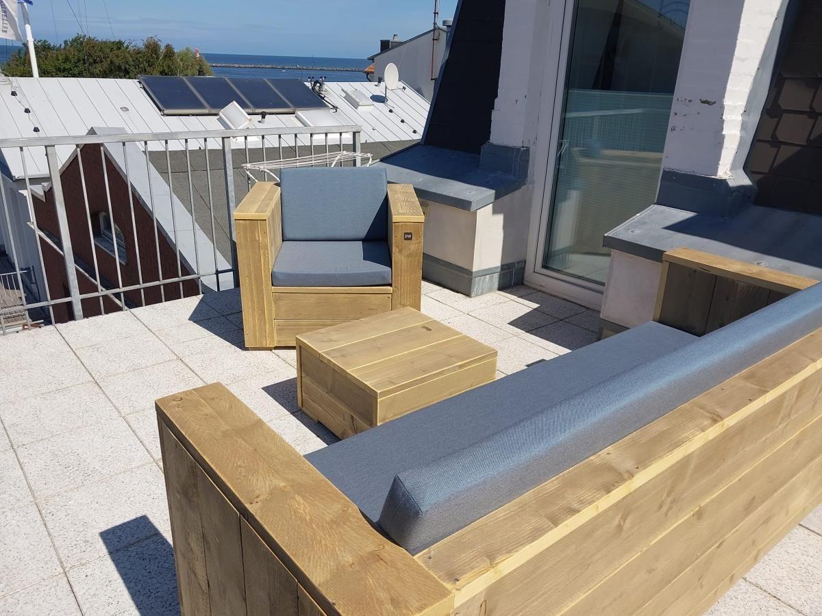 Terrasse mit Sitzgelegenheiten und Meerblick. Hintergrund: Strand und Boot.