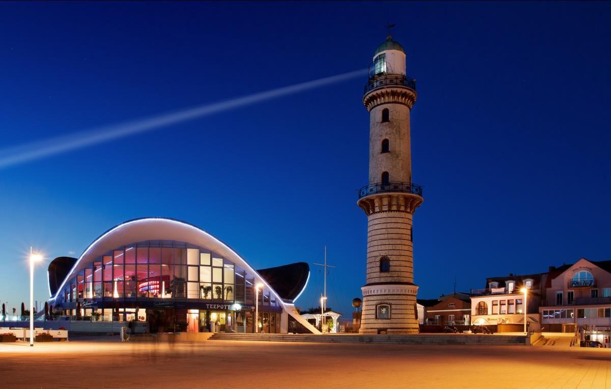 Haus mit Balkonen und Leuchtturm im Hintergrund