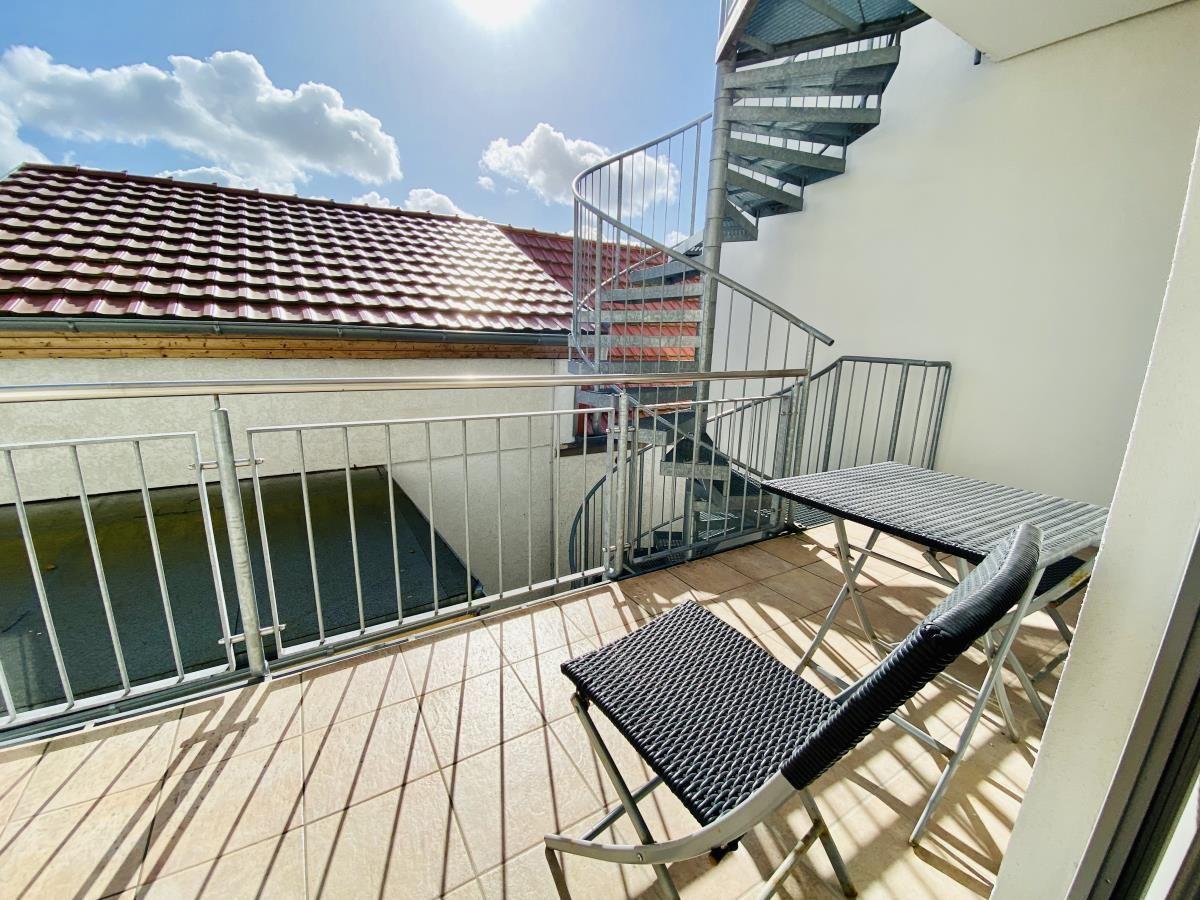 Modernes Haus mit Balkonen und Garagenanlage an sonnigem Tag.