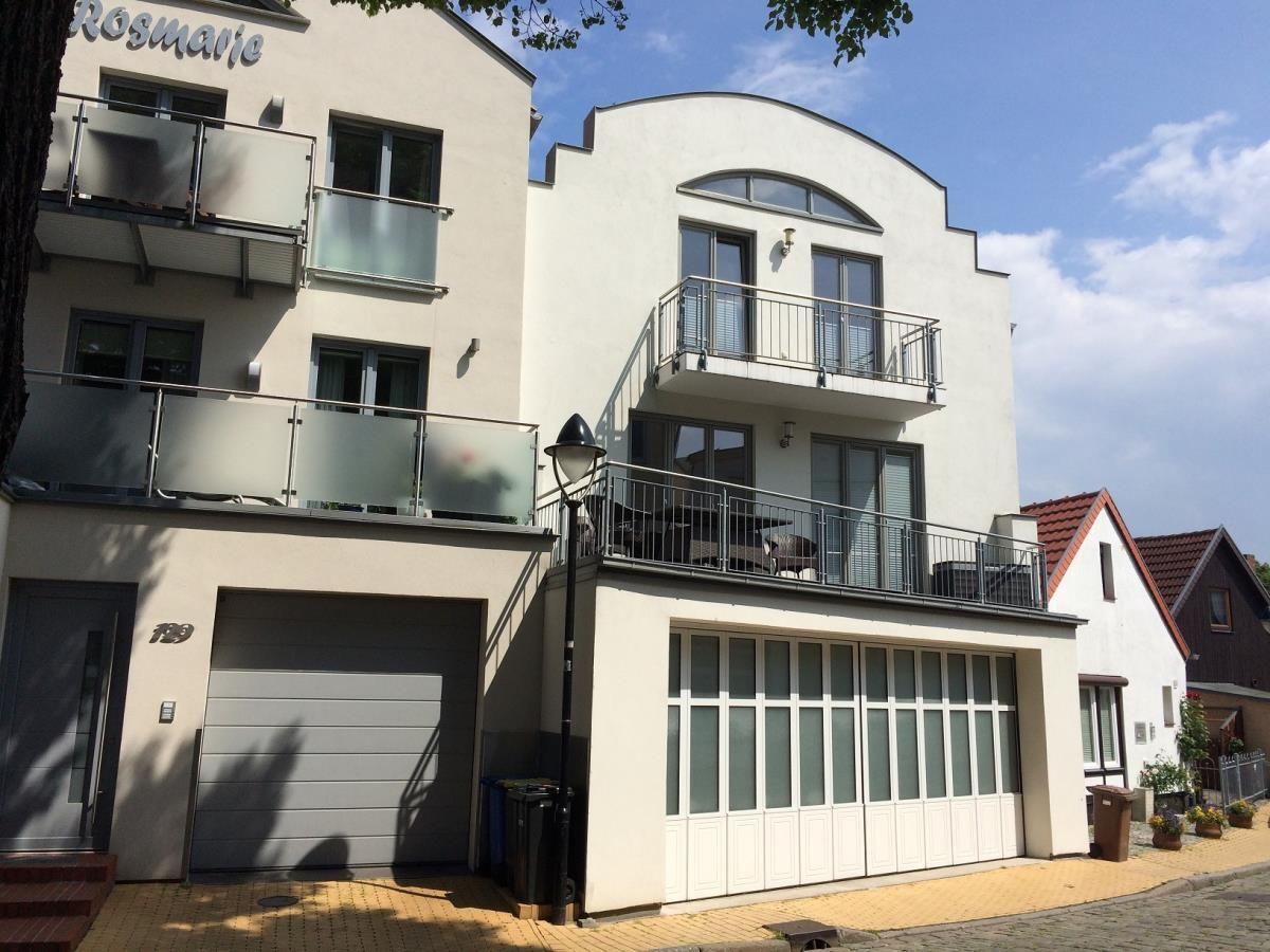 Kurze Straße mit Fachwerkhäusern und Blumenkästen an den Fenstern.