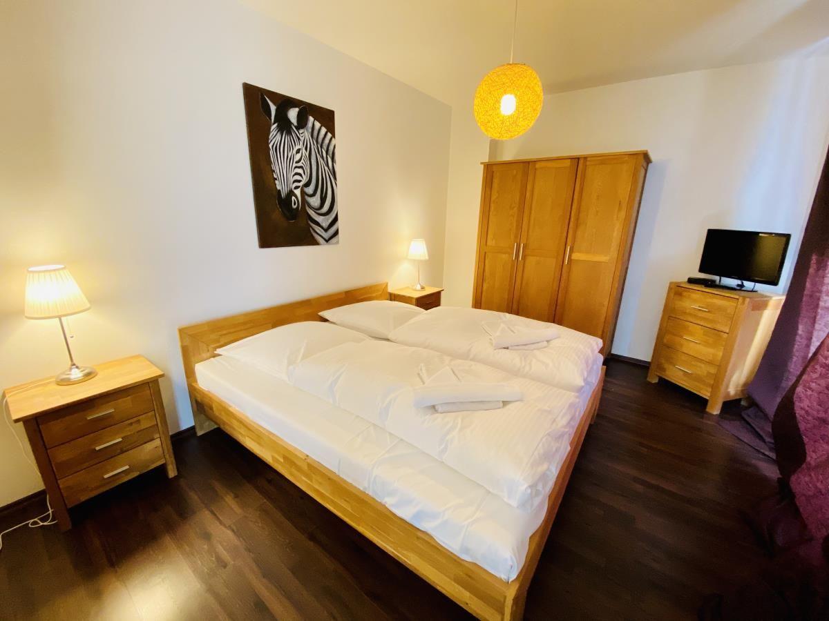 Schlafzimmer mit Holzbett, Kleiderschrank und Fernseher. Spiegel und Bank im Flur.