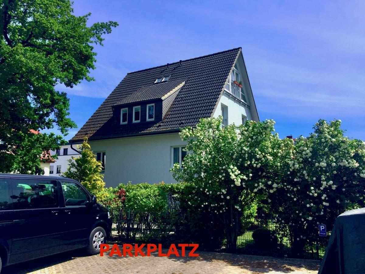 Garten mit Rasenfläche, Sitzgelegenheit und Grillhütte unter Bäumen.
