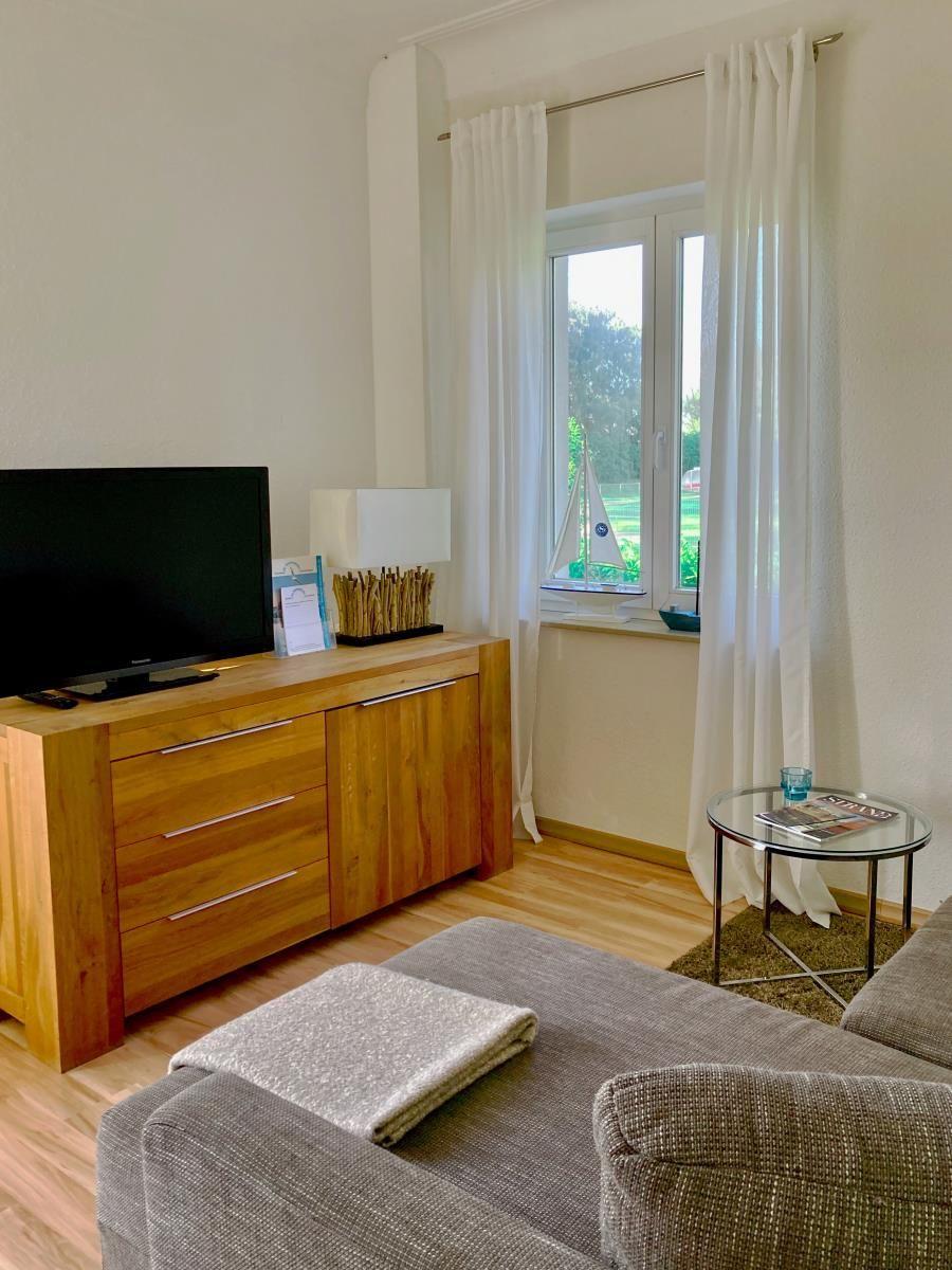 Holztisch mit Stühlen vor Fenster mit Blick auf Balkon und Grün.