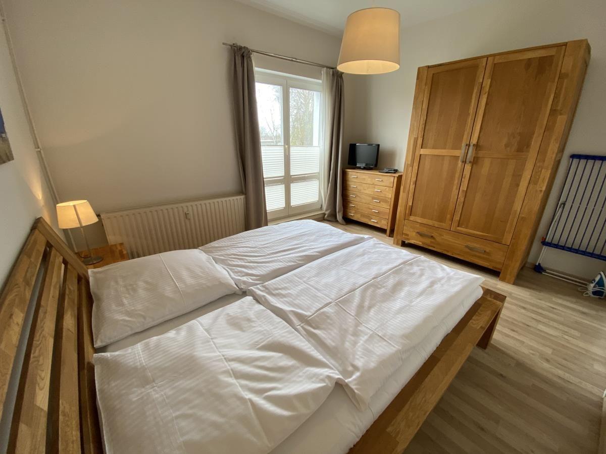 Schlafzimmer mit Doppelbett, Holzmöbel und Fenster mit Blick nach draußen.