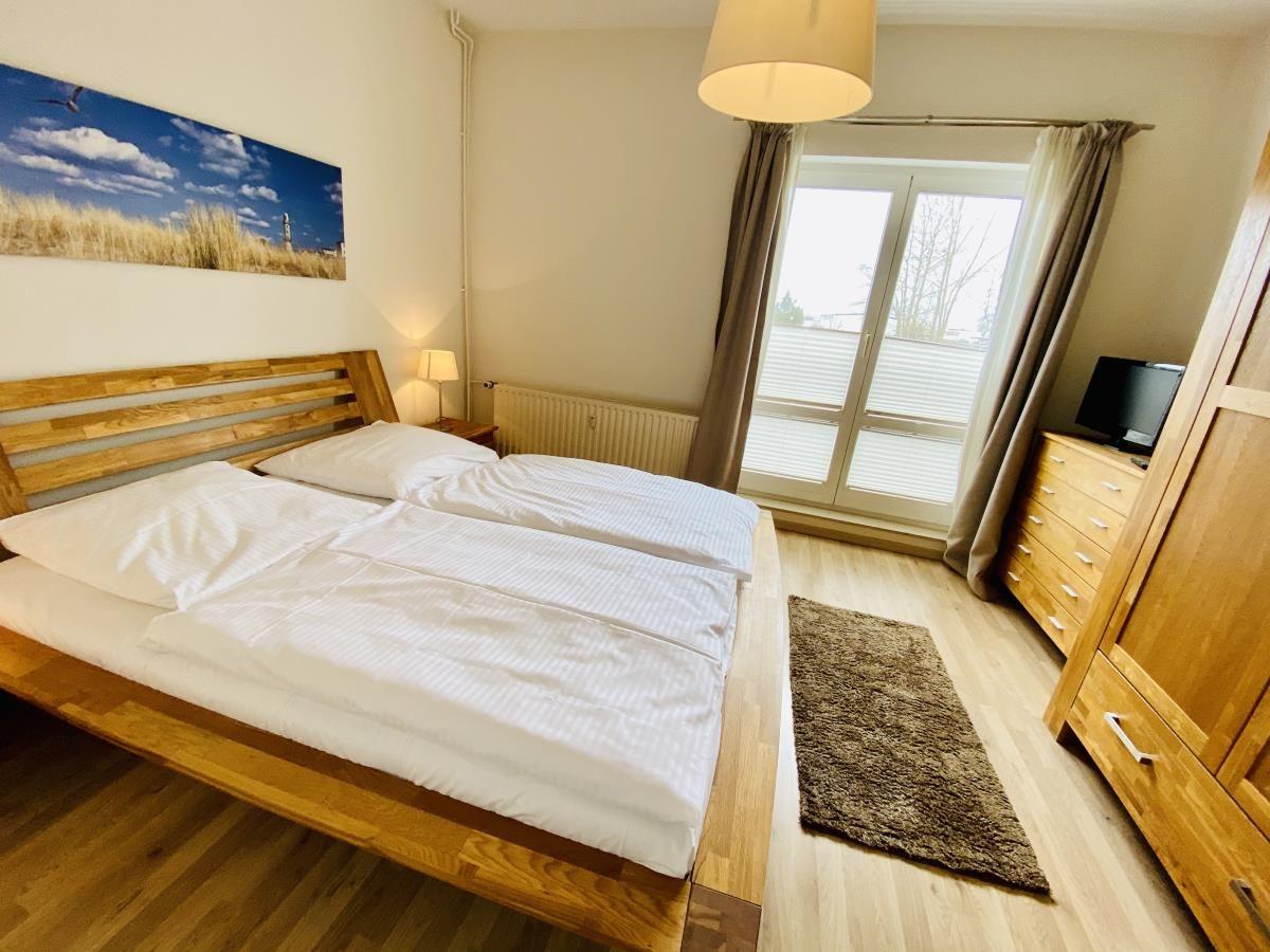 Zwei Einzelbetten, Holzboden, Fenster mit Vorhängen, Deckenleuchte, Teppich
