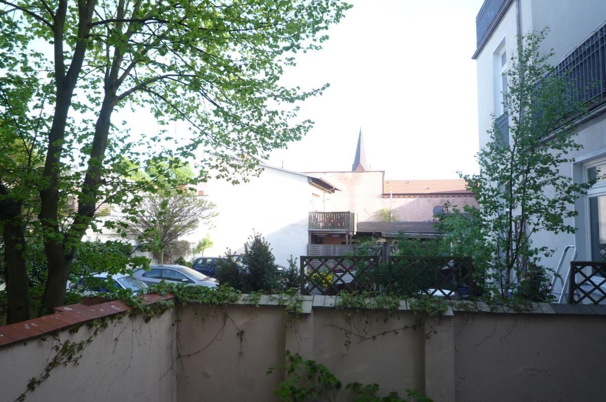 Terrasse mit Tisch, Stühlen und Pflanzen vor einem Haus mit Fenstern.
