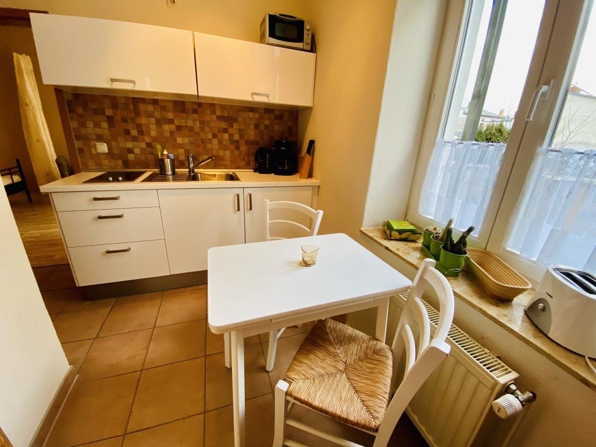 Küche mit weißen Schränken, Mosaikwand und Küchenzeile mit Tisch.