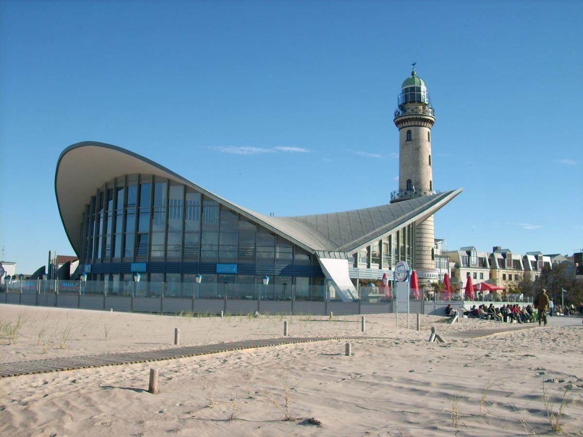 Lichtturm neben modernem Gebäude und Sanddünen am Strand