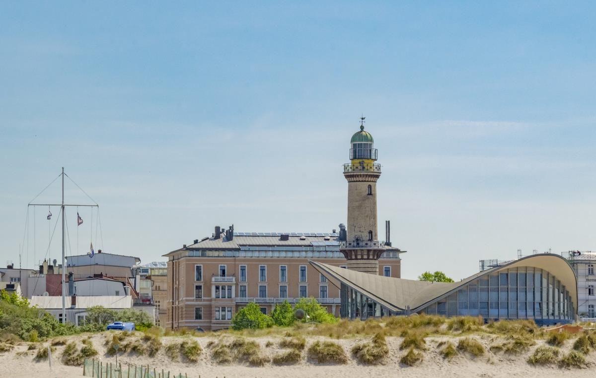 Eine Hand hält einen Eisbecher mit Schokolade und weißem Eis am Strand.