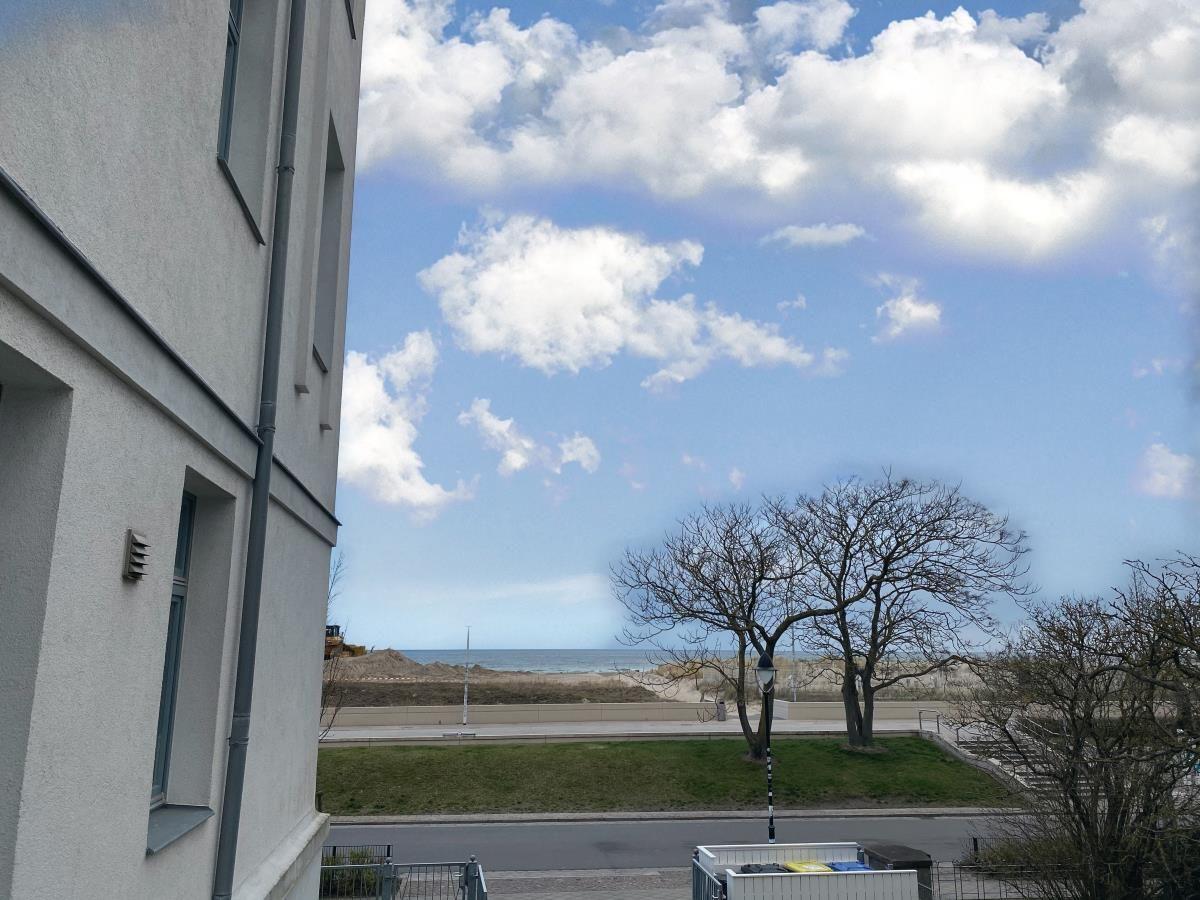 Wohnzimmer mit Sofa, Couchtisch und Fernseher. Durchgang zur Terrasse mit Blick.