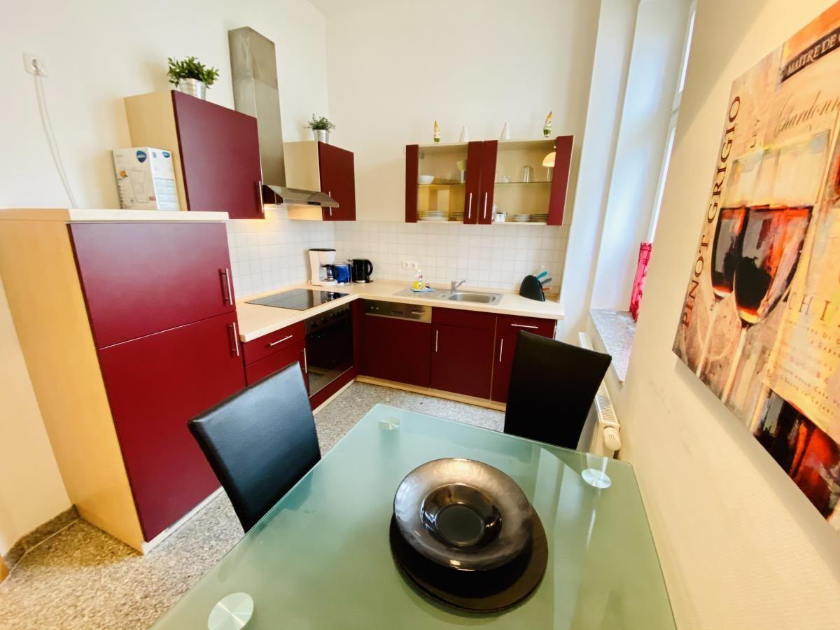 Flur mit Holzboden, Teppich und Blick in Wohnzimmer mit Couch und Tisch.
