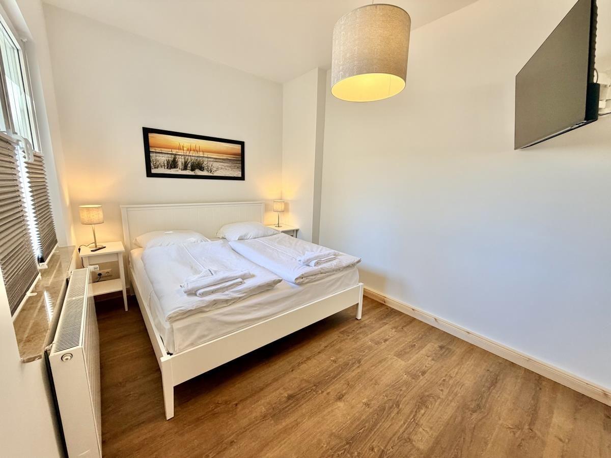 Zwei Betten mit weißen Bettwäsche, Spiegelwand und Fernseher an der Wand.