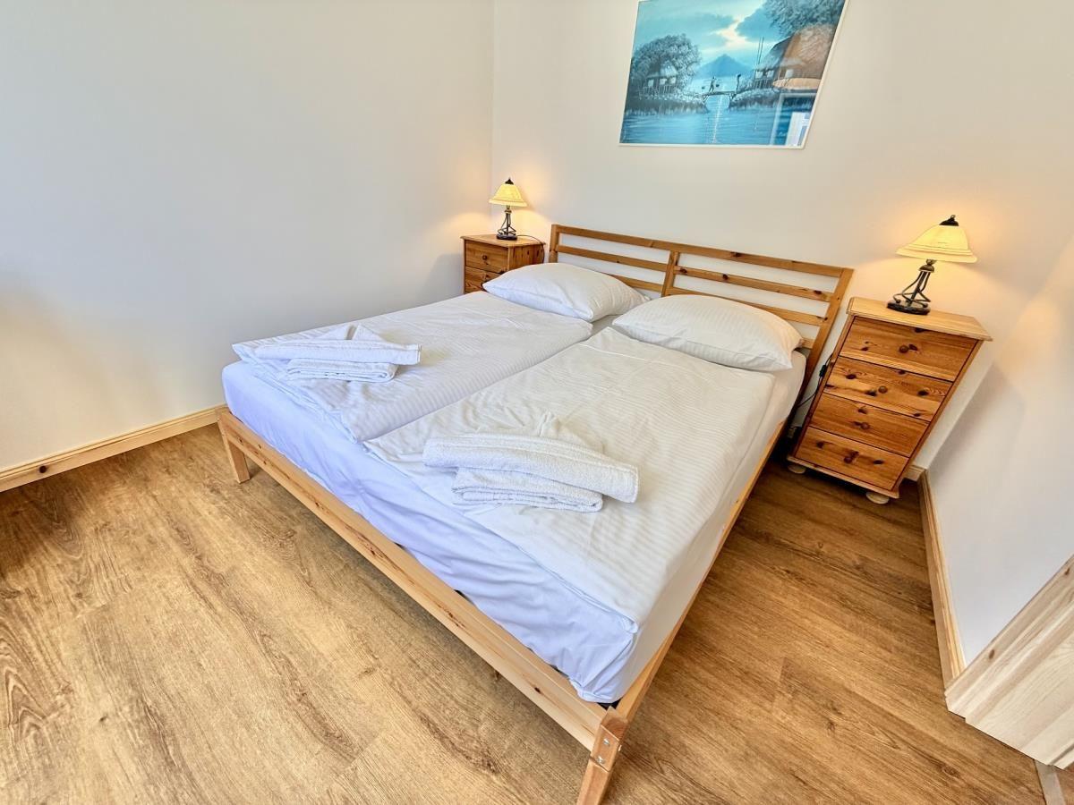 Schlafzimmer mit Bett, Schreibtisch und Fenster. Holzmöbel und Holzboden.