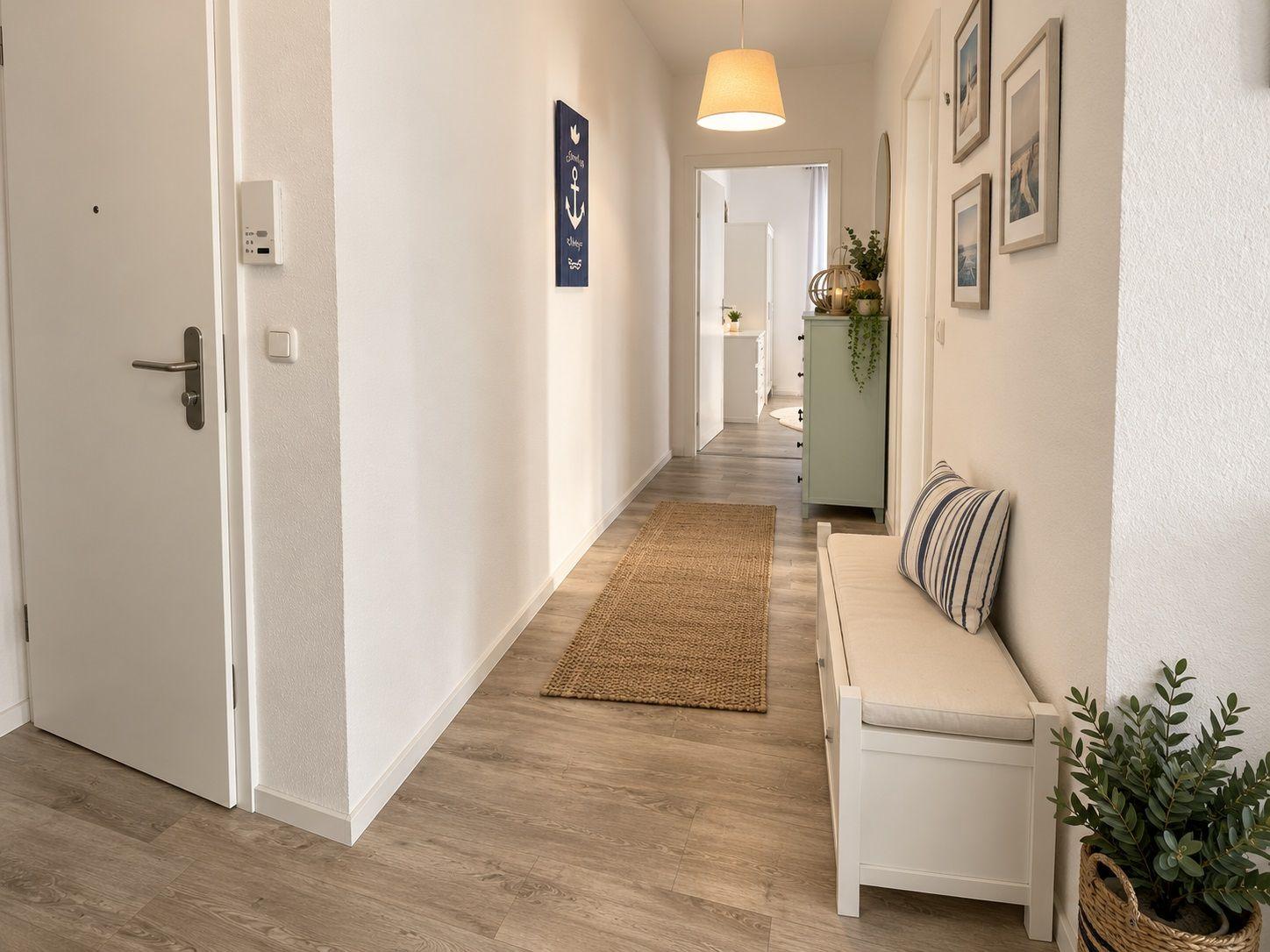 Flur mit Holzboden, weißer Bank und Wanddekoration