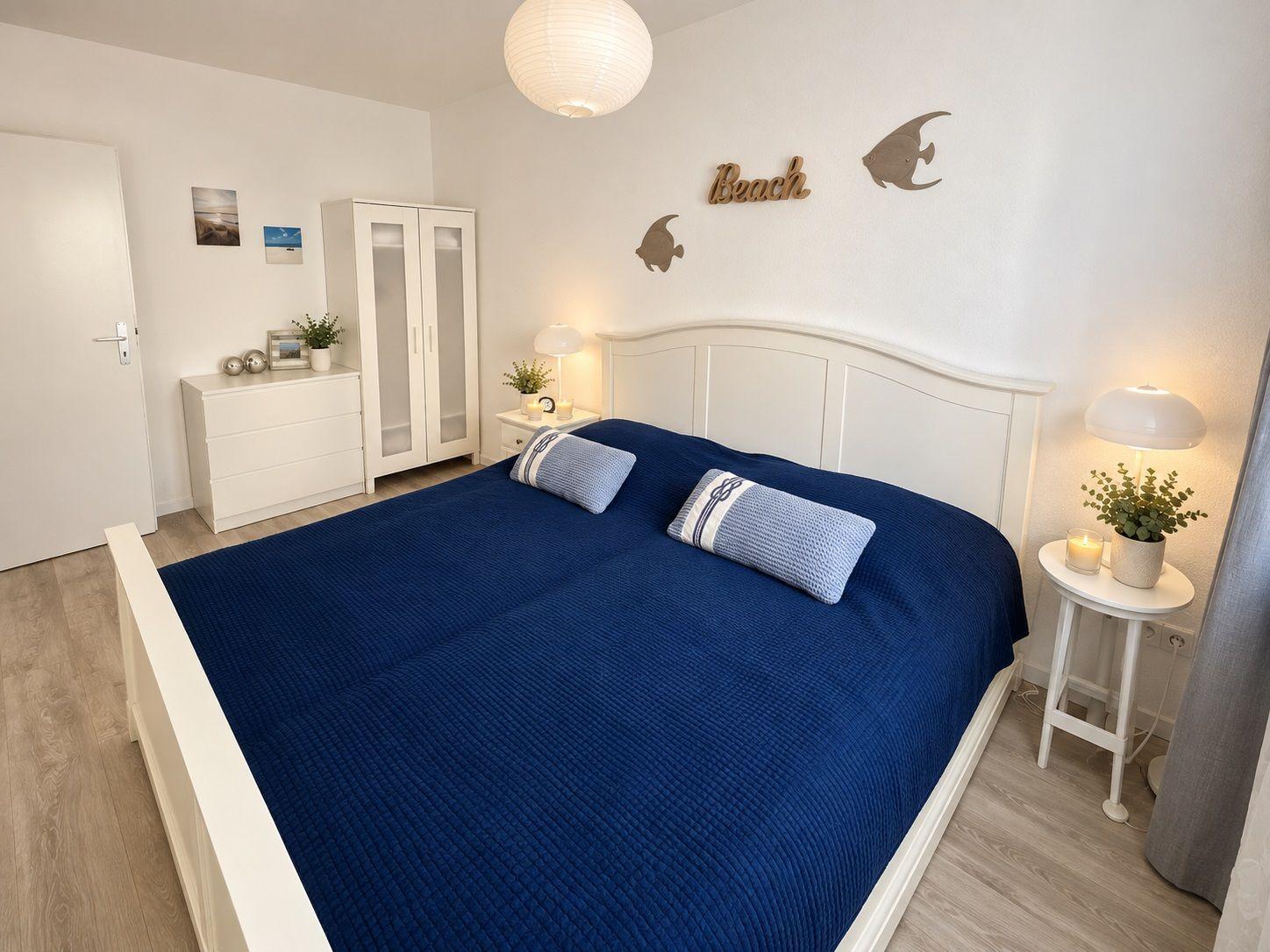 Schlafzimmer mit Bett, Kleiderschrank und Wanddekoration.