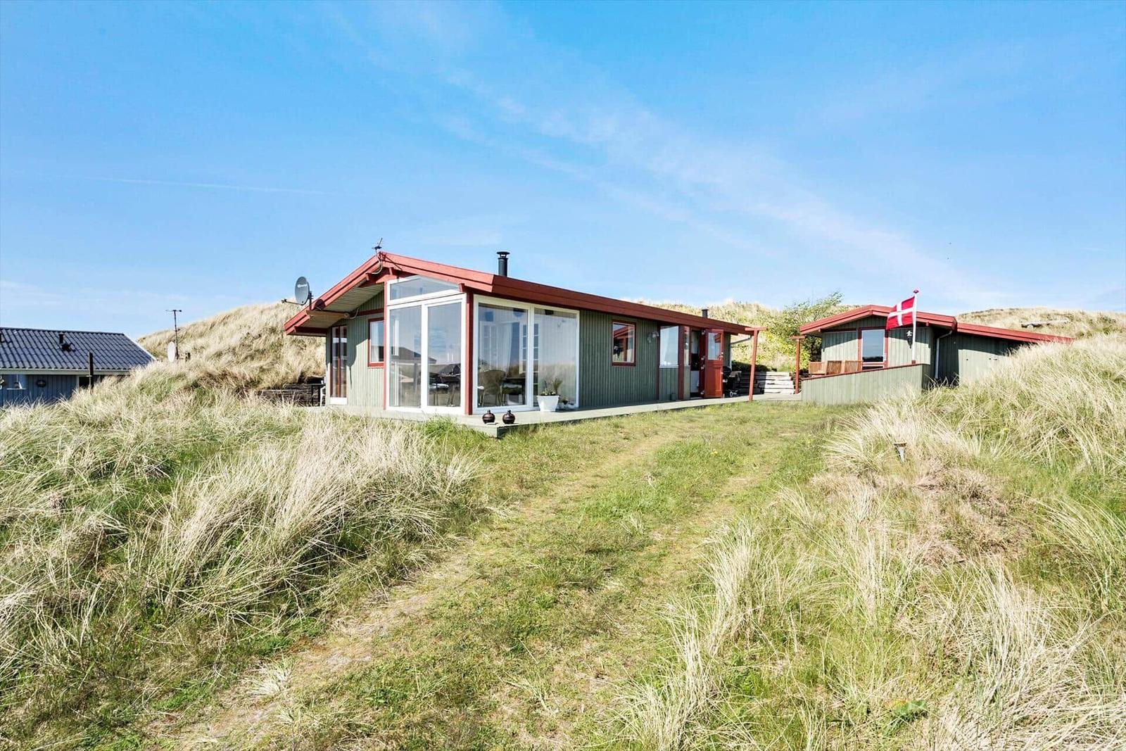 Weitläufige Dünenlandschaft mit Blick auf das Meer unter blauem Himmel.