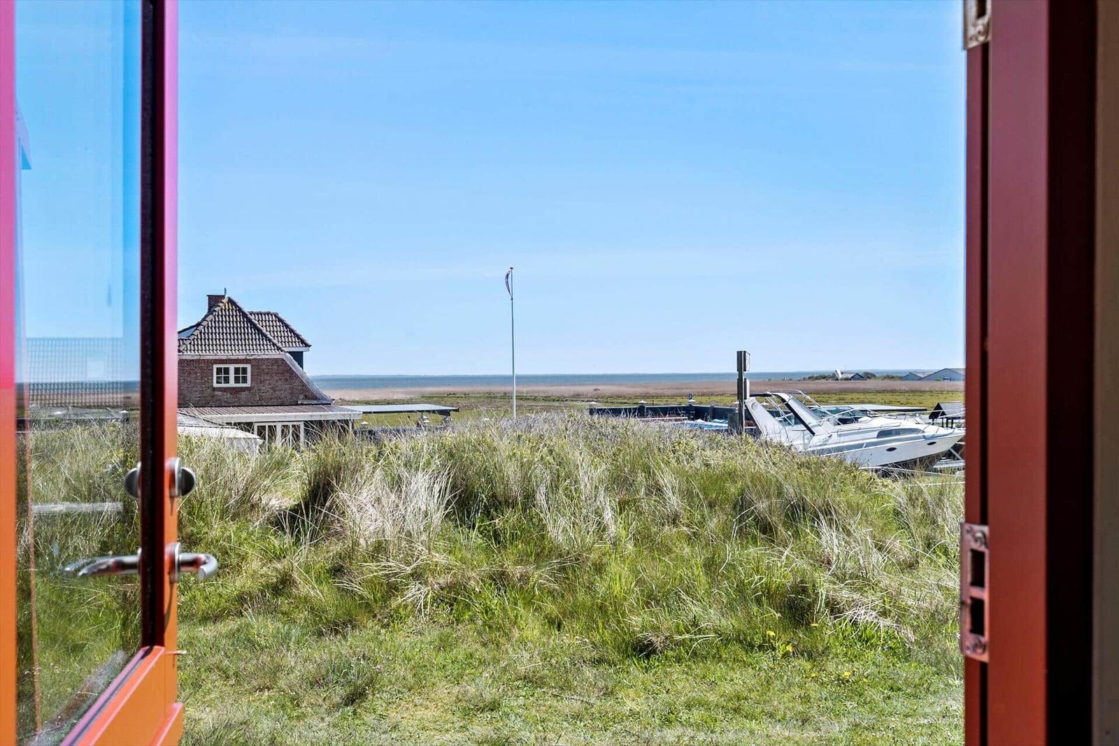 Haus mit Blick aufs Meer und Windrad. Grasland im Vordergrund.