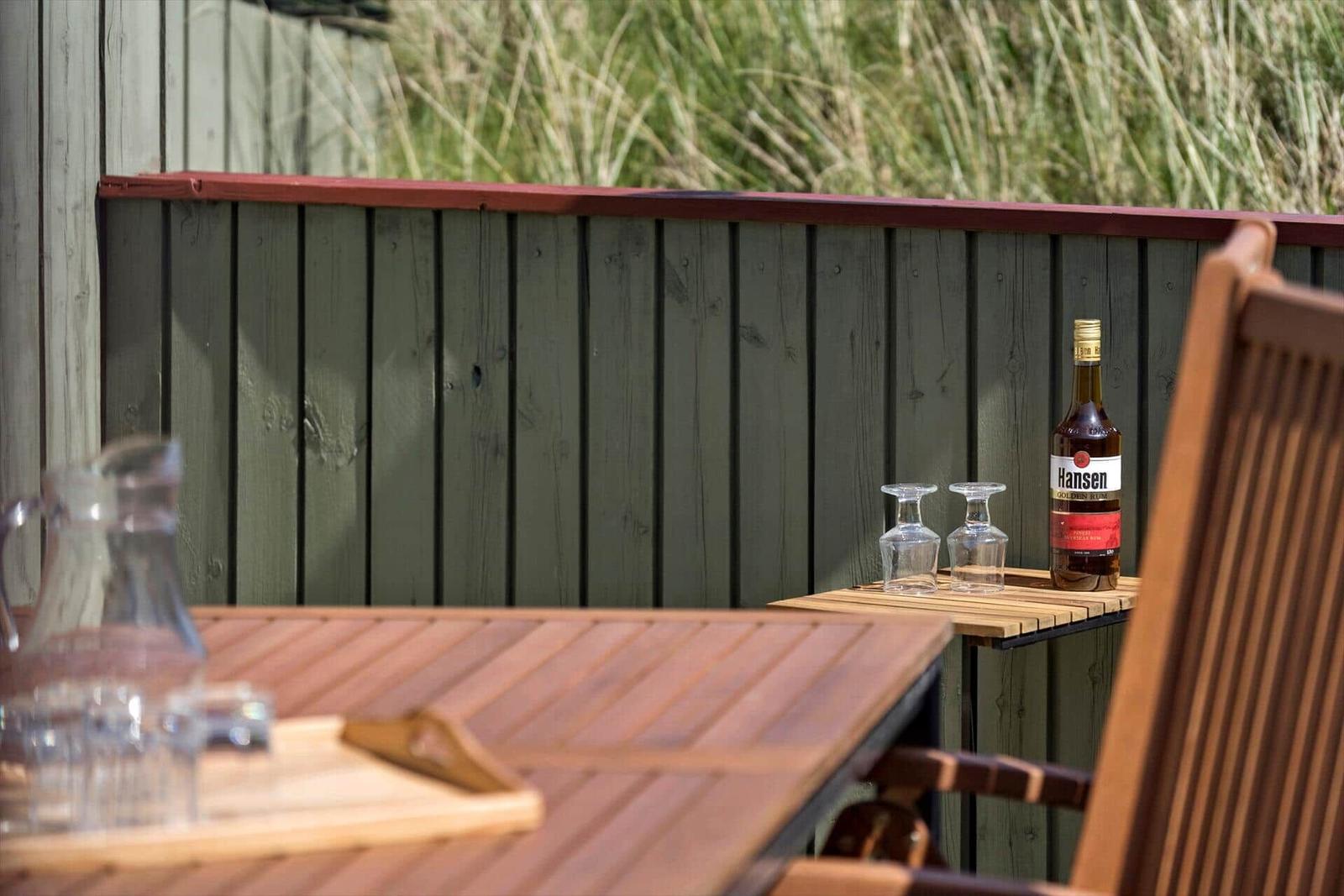 Terrasse mit Tisch und Stühlen vor einem Holzhaus mit dänischer Flagge.