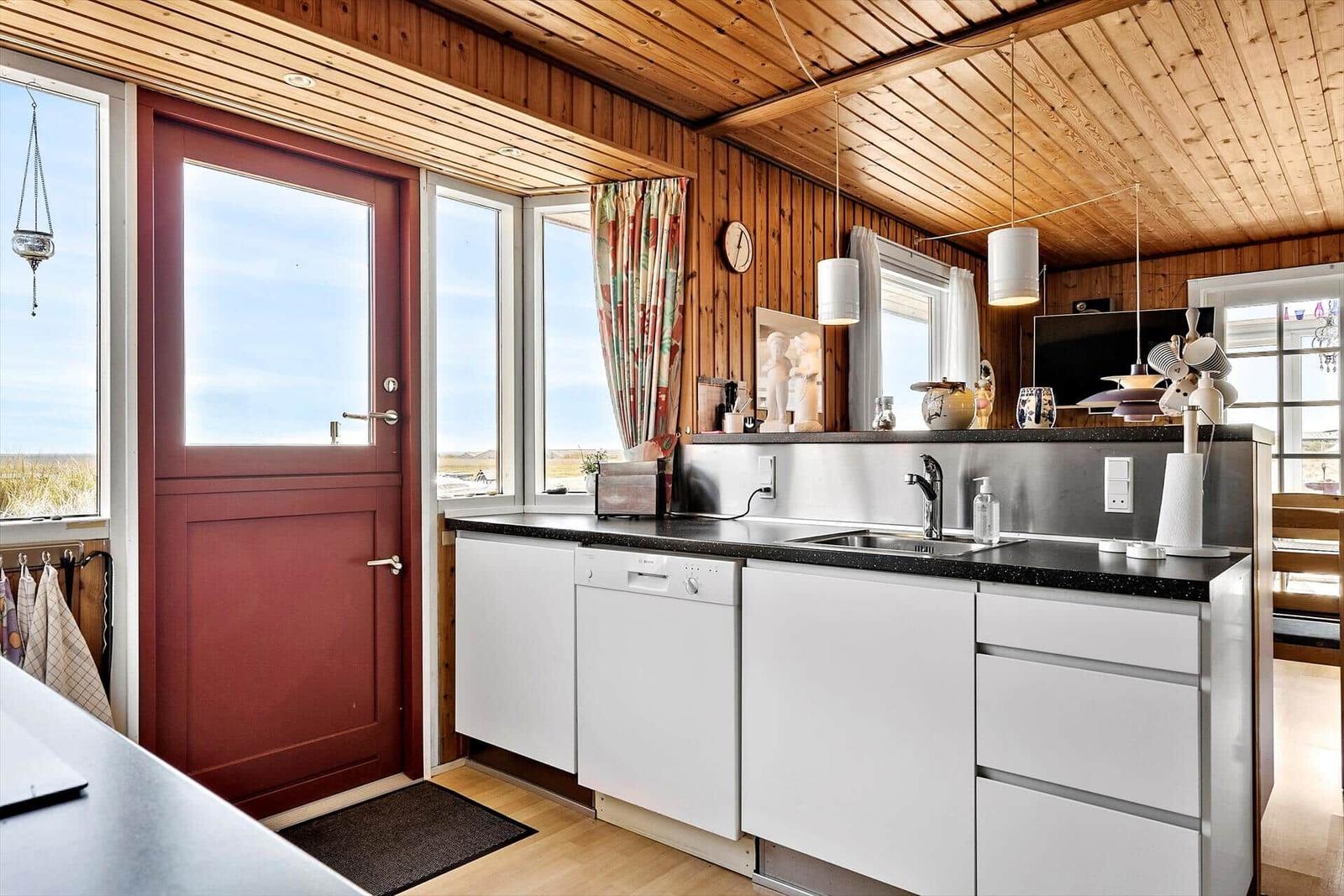 Holzgestell mit zwei Betten, Fenster mit Blick auf Gras, Wandlampen und Stuhl.