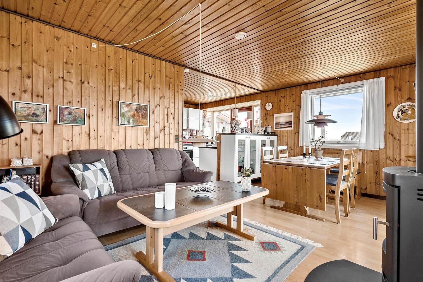 Durch eine Tür blickt man auf eine Wiese mit Booten und einem Haus am Strand.