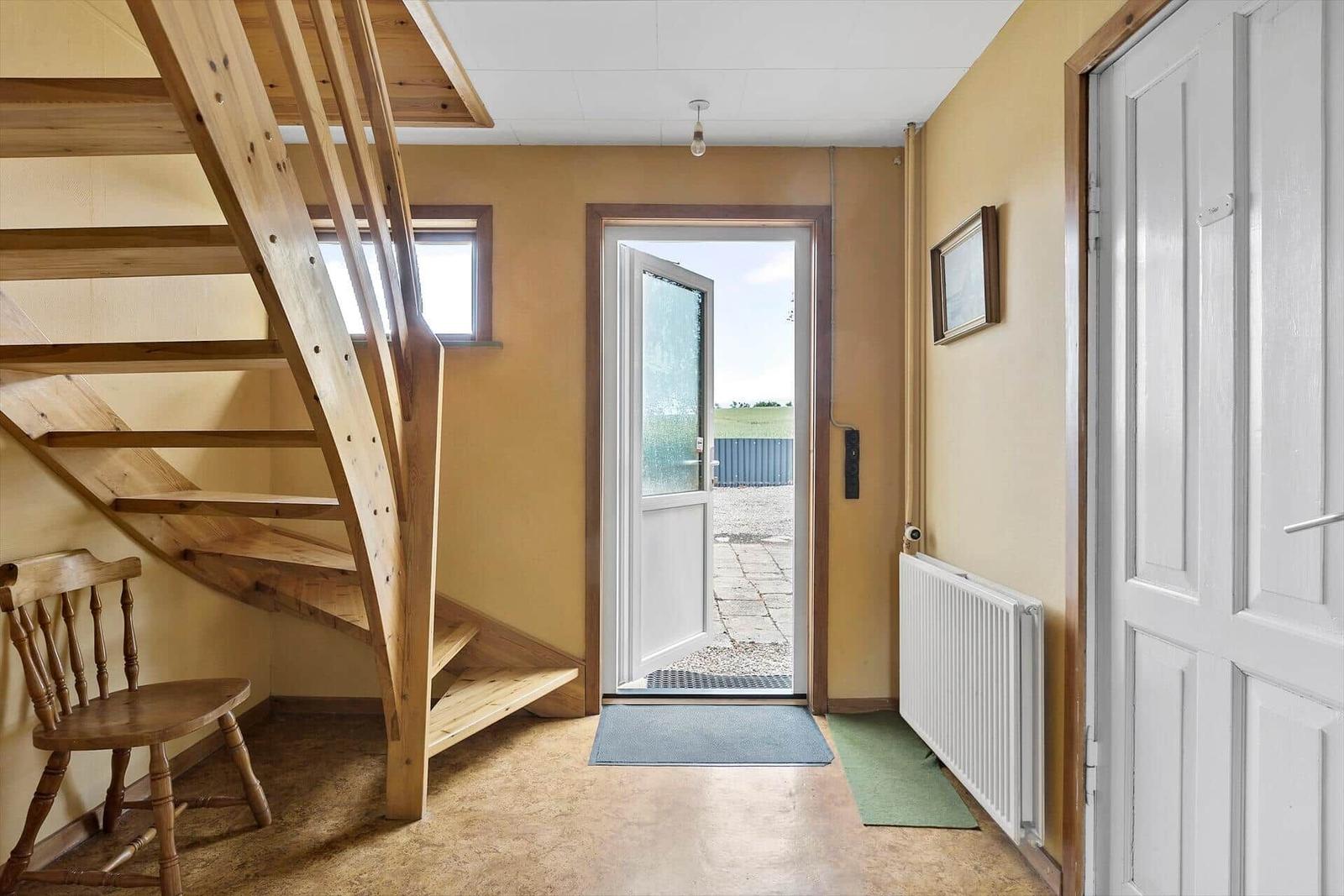 Bedroom with sloped ceiling, wooden floor, and windows. Bed, sofa, and dresser are visible.