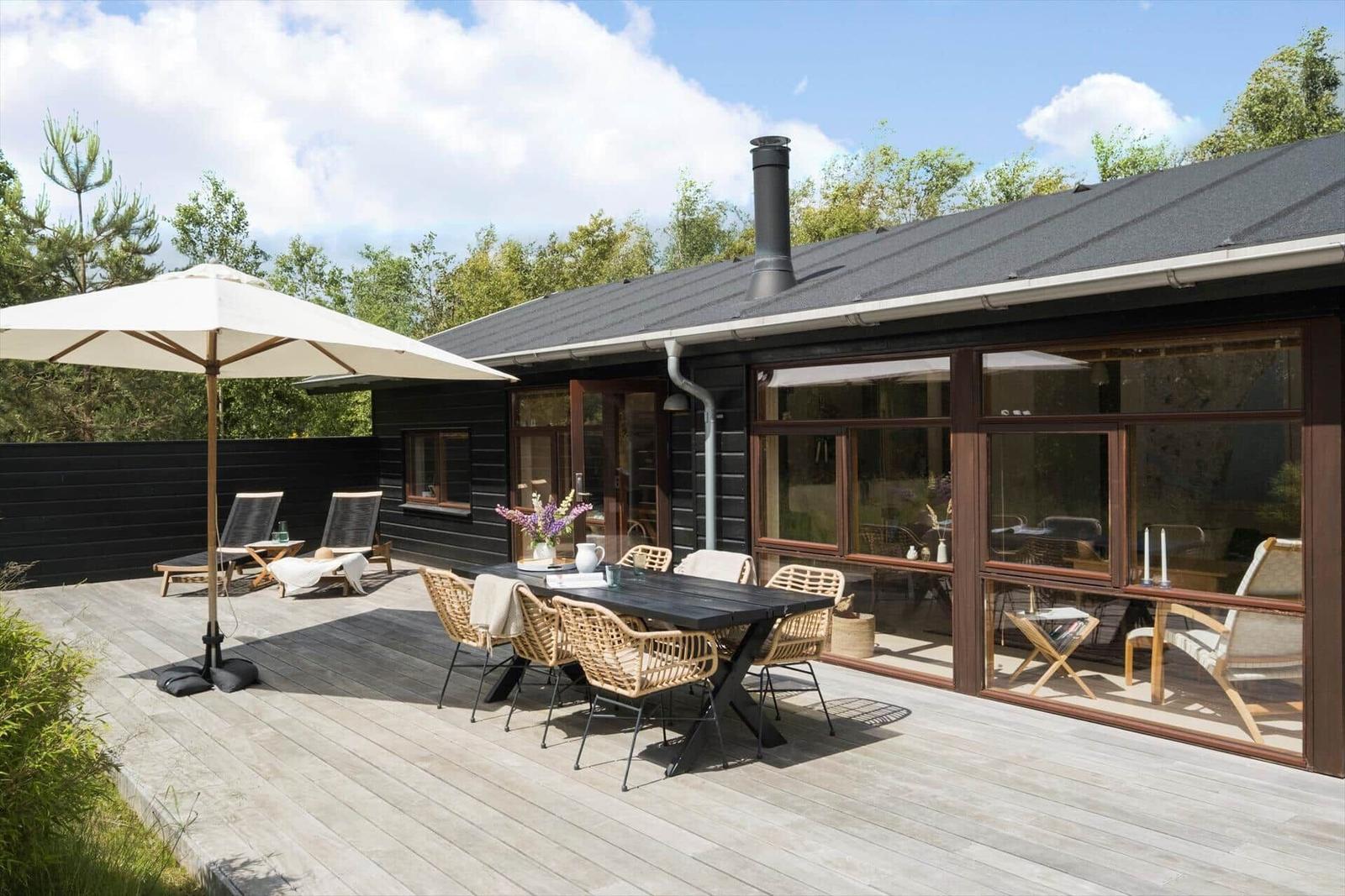 Essbereich mit Holztisch, Stühlen und Wandbild. Durchgang zur Terrasse mit Gartenblick.