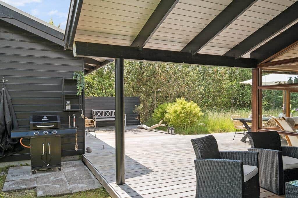 Terrasse mit Loungemöbeln, Esstisch und Blumenarrangement.