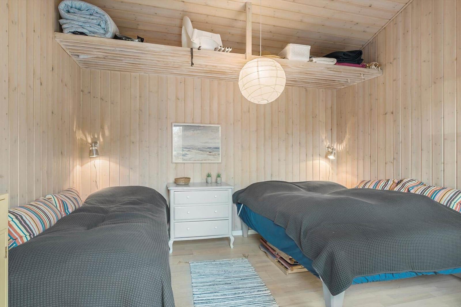 Holztisch mit Stuhl und Kerze unter Rattanleuchten.
