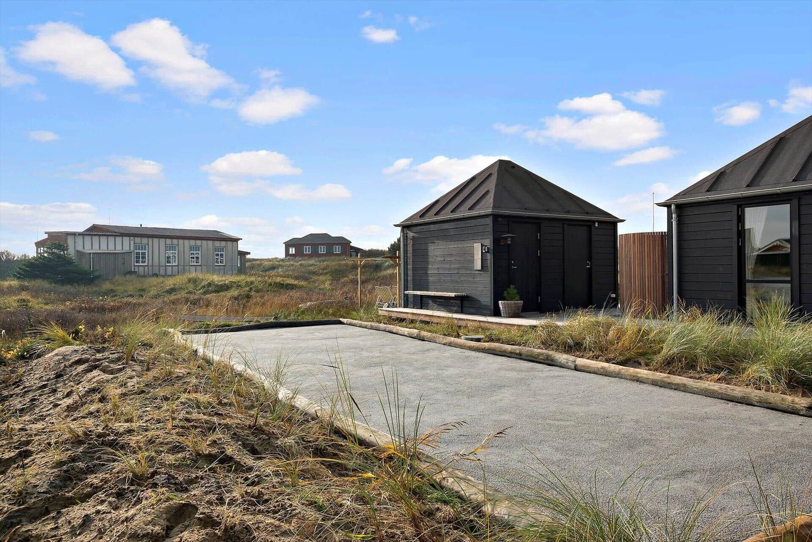 Schwarze Holzhütte mit Terrasse, Liegen und Whirlpool im Freien.