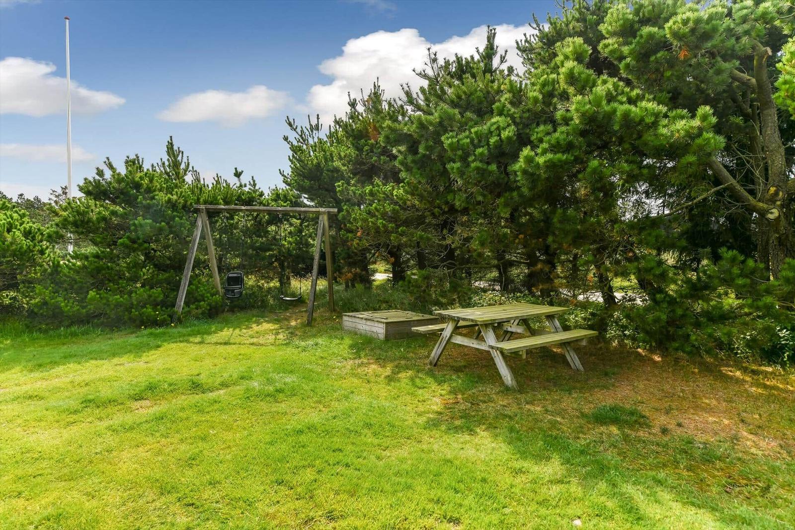 Ein Haus mit Garten, Grillplatz und Flagge unter blauem Himmel.