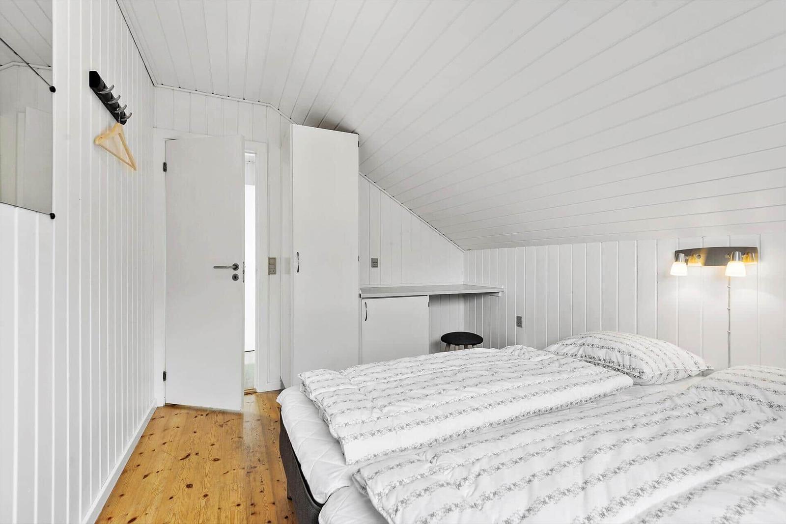 Hinter einem Schaukelgestell steht ein graues Haus mit Garten und Bäumen.