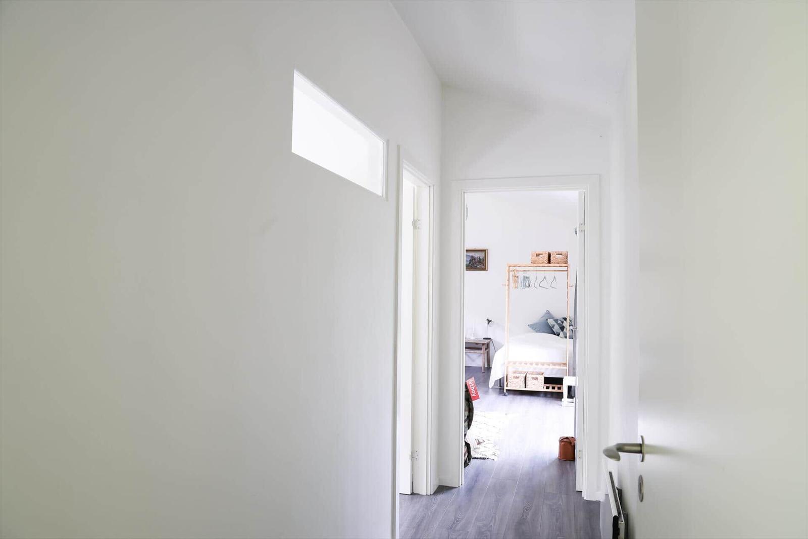 Schlafzimmer mit Bett, Fenster und Metallregal mit Körben.