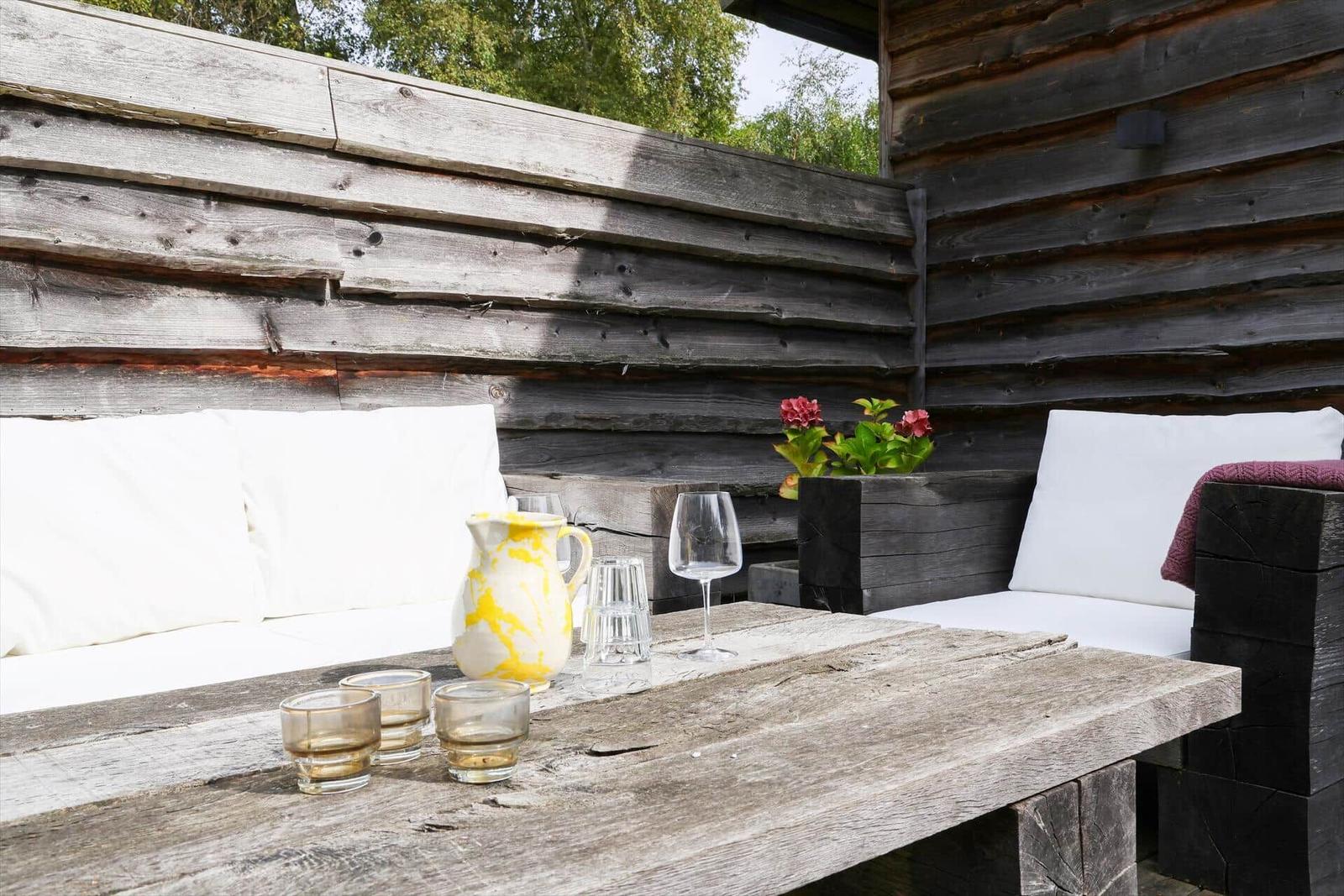 Ein Tisch mit Blumen, einer Kanne und einem Becher. Hintergrund: Fenster und moderne Beleuchtung.