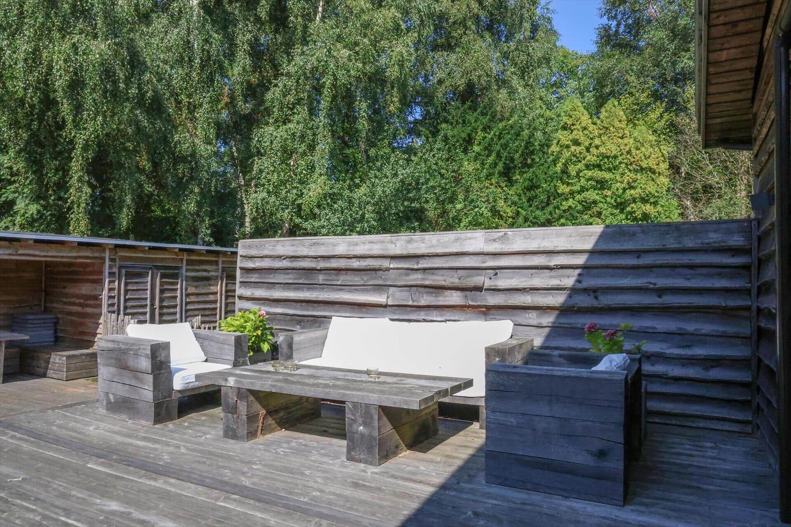 Wohnzimmer mit grauem Sofa, rustikalem Tisch und Ledersesseln.