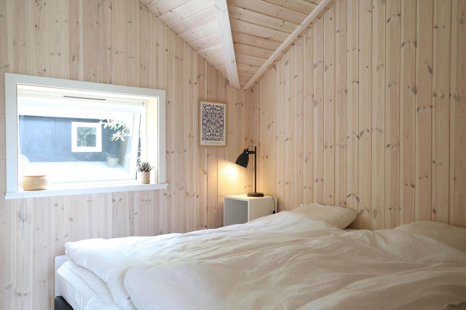 Holzterrasse mit Bänke, Pflanzen und Fenster an schwarzem Haus