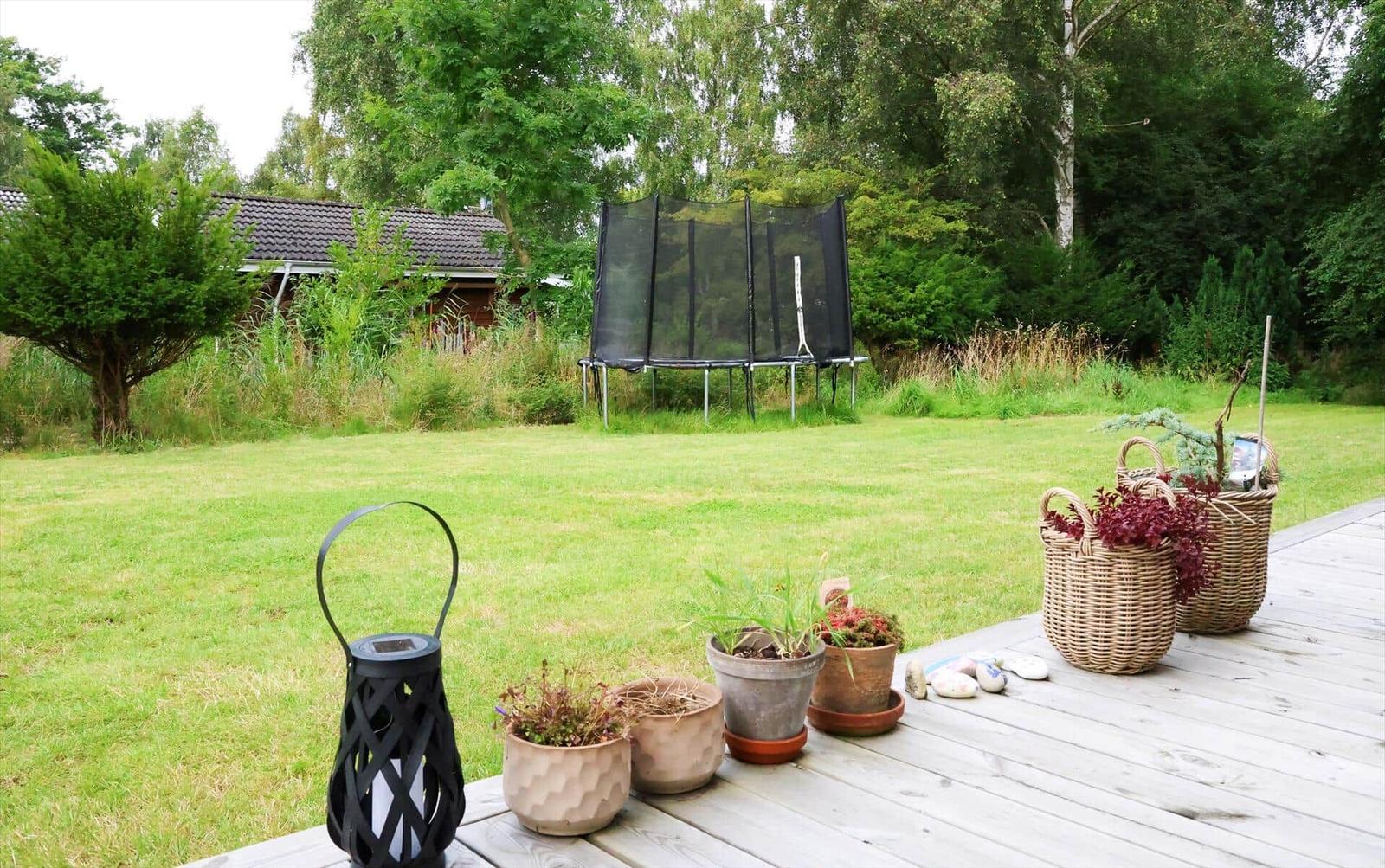 Wohnzimmer mit Sofa, Tisch und Fenster. Holzwände und -decke. Bilder und Pflanzen.