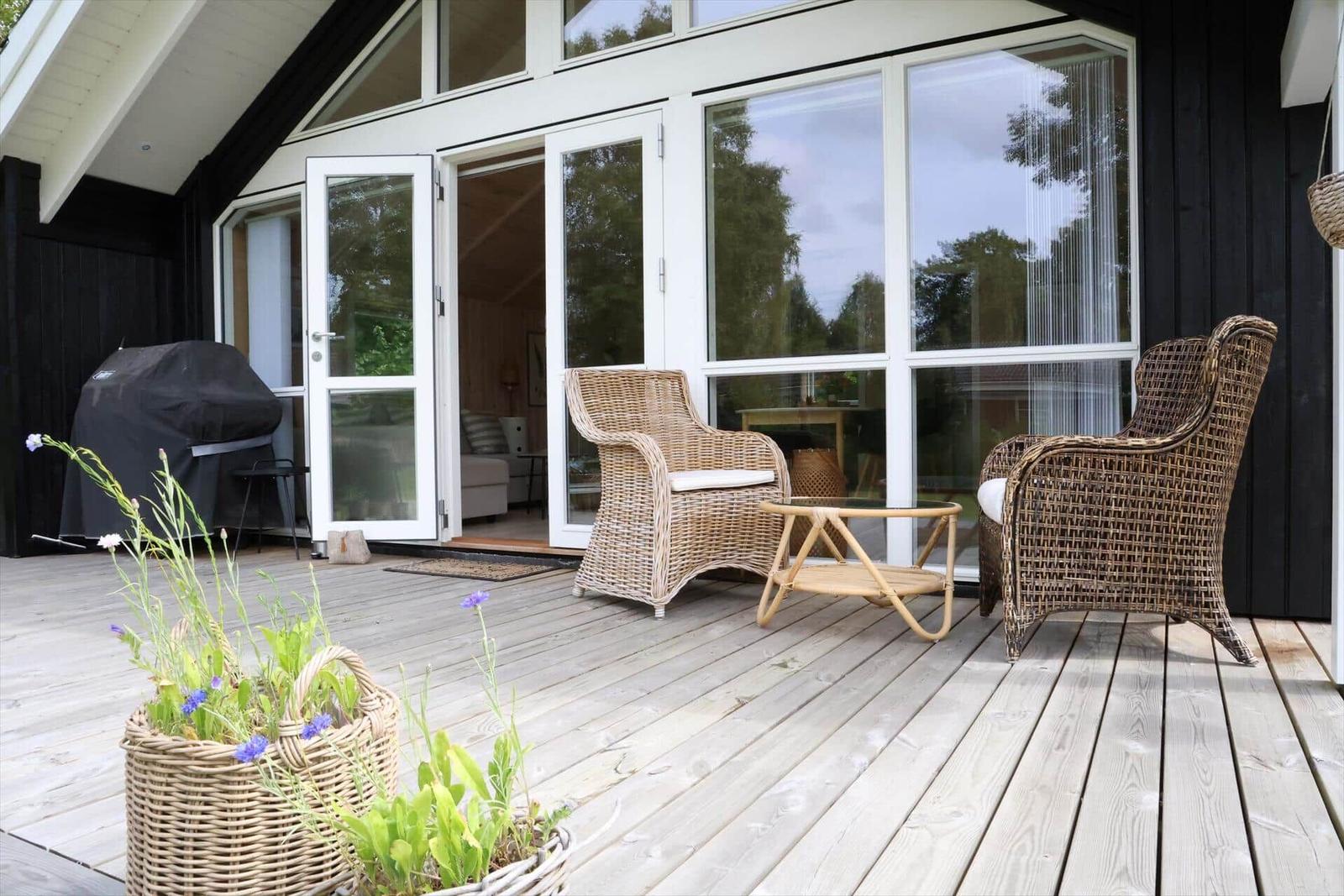 Ein Raum mit Holzwand und -decke, großem Fenster, Sofa, Tisch und Küchenutensilien.