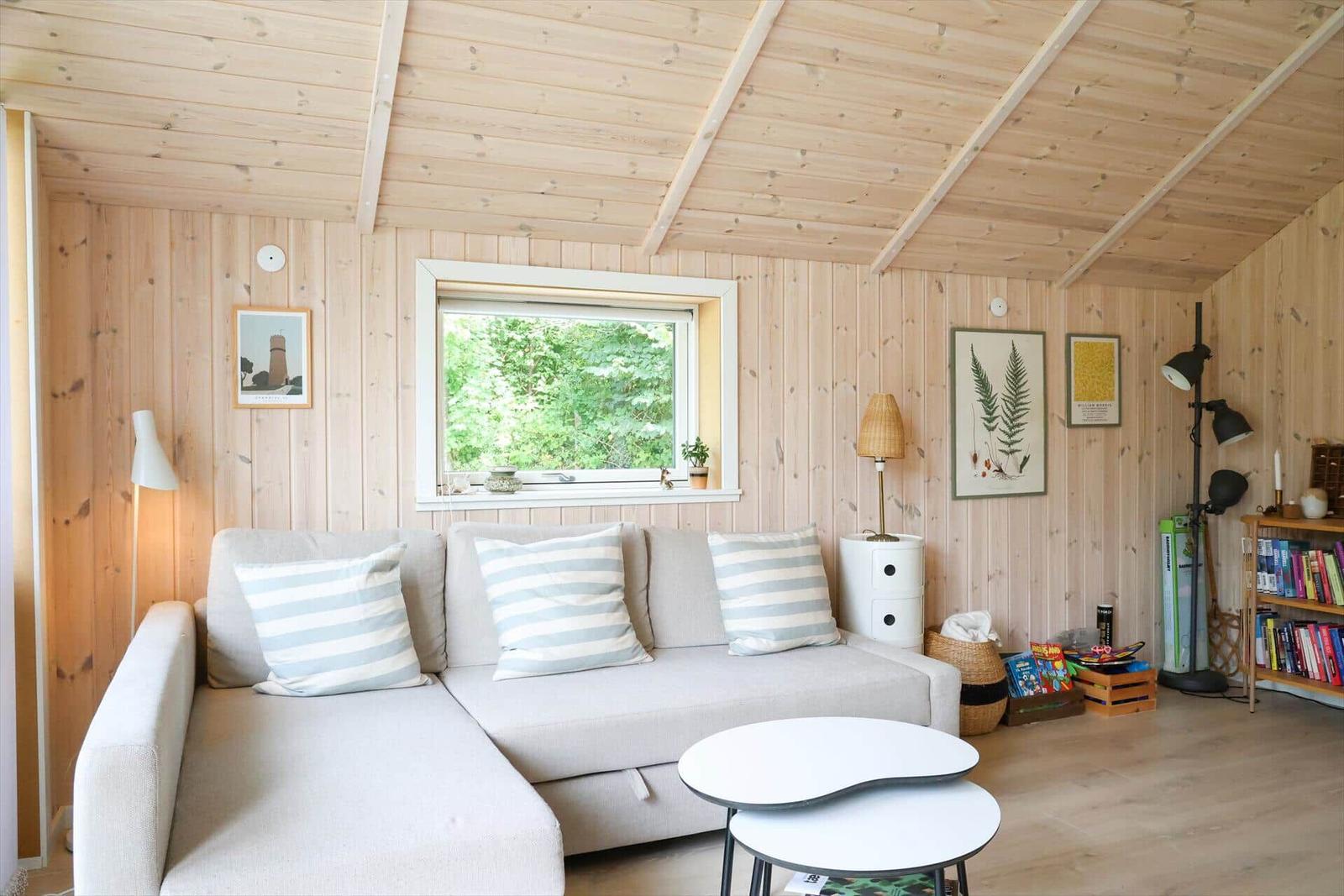 Küche mit Holzwänden und Dachboden. An der Wand hängen Bilder und ein Hut.