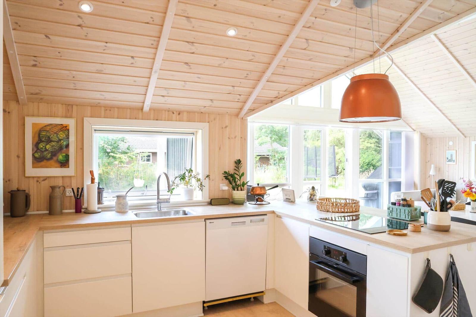 Ein Haus mit großem Balkon, Grill und Gartenmöbeln. Umgeben von Bäumen und Gras.