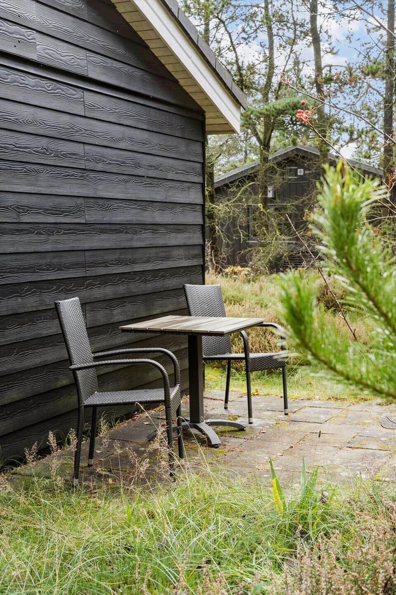 Terrace with table and chairs, view of black houses and trees.
