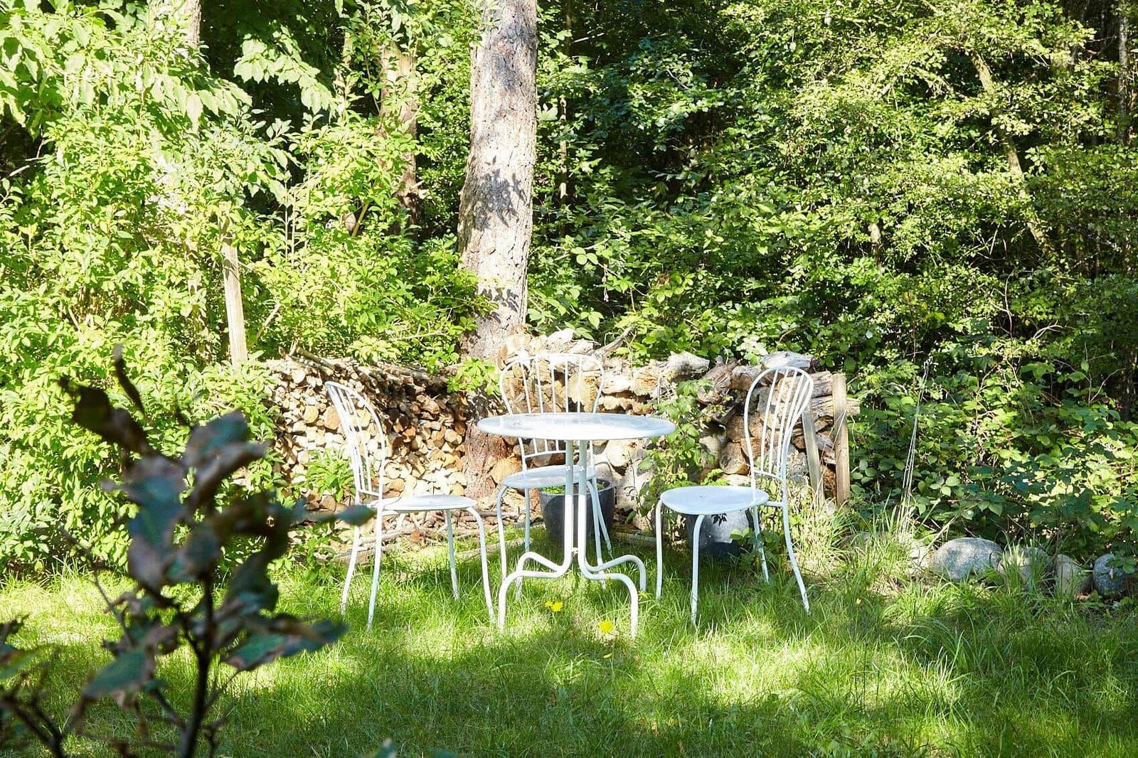 Wohnküche mit Holzboden, Fernseher, Stühlen und Fenstern zum Garten.