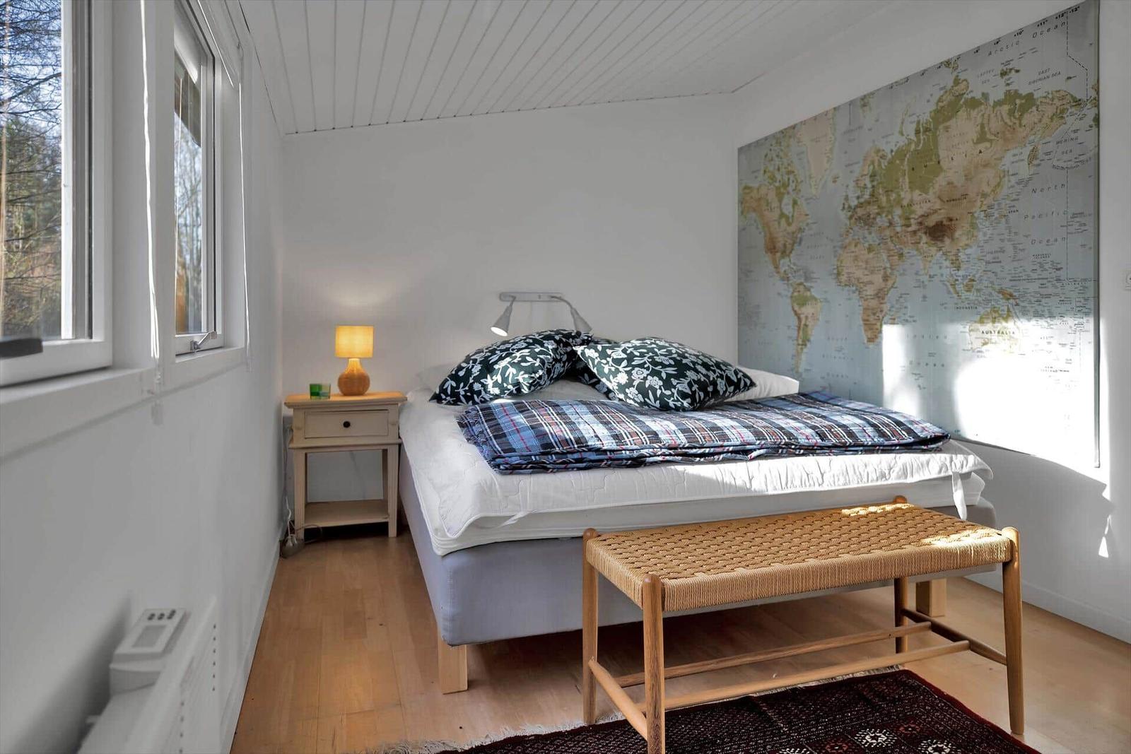 Schwarzes Holzhaus mit offener Tür und Pflanzen auf dem gepflasterten Vorplatz.