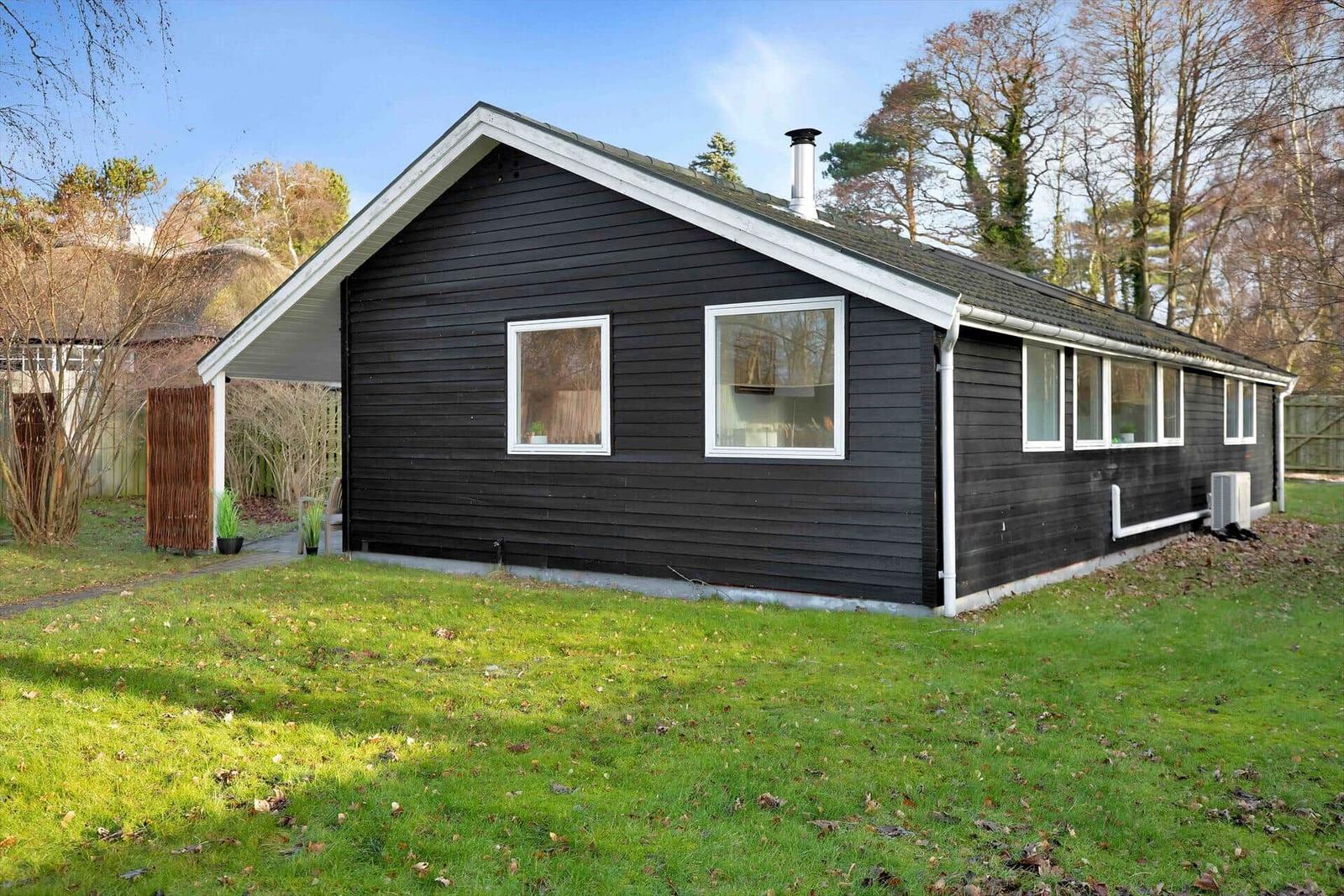 Moderne Strandhütte auf Dünen mit Blick auf das Meer und einen sandigen Strand.