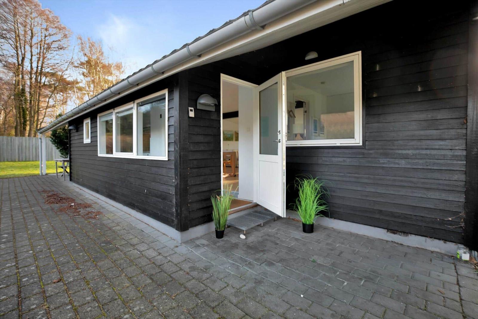 Esszimmer mit Holztisch, Stühlen und Teppich. Im Hintergrund Küche und Wohnbereich.
