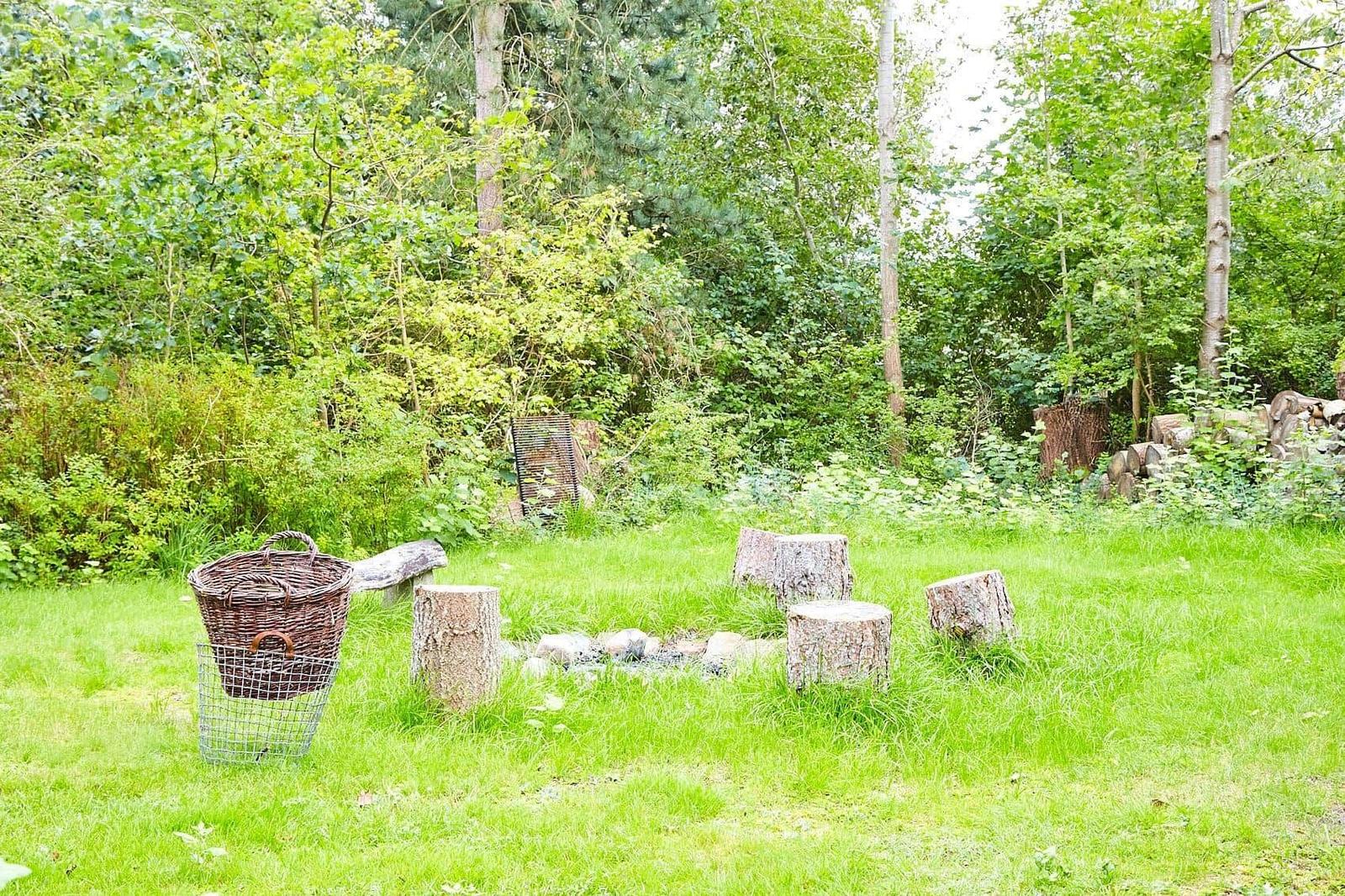 Garten mit Holzschaukel, Laterne und Skulptur unter Bäumen.