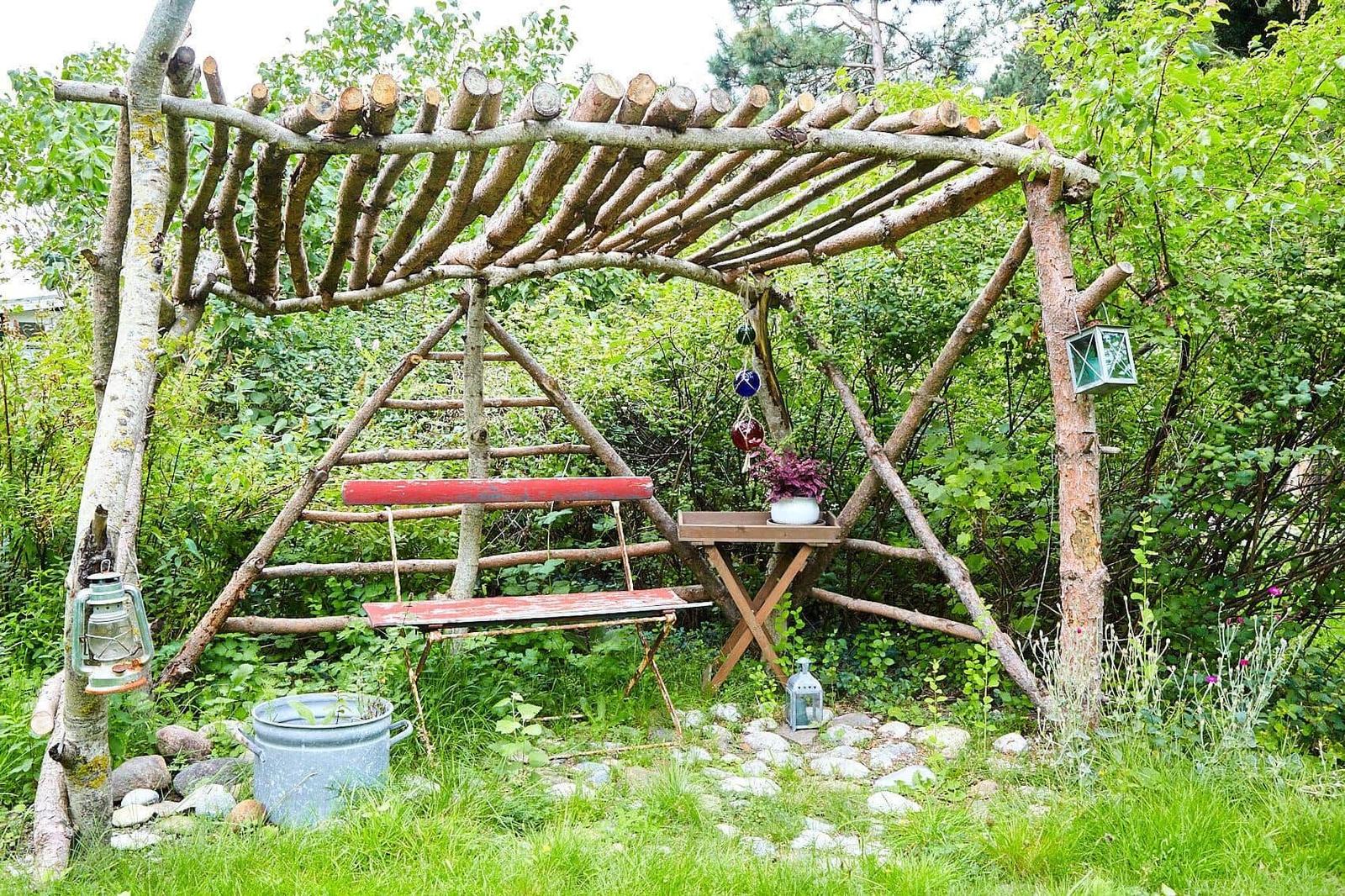 Garten mit Baum, Sträuchern und Blumenkästen. Eine Laterne hängt am Baum.