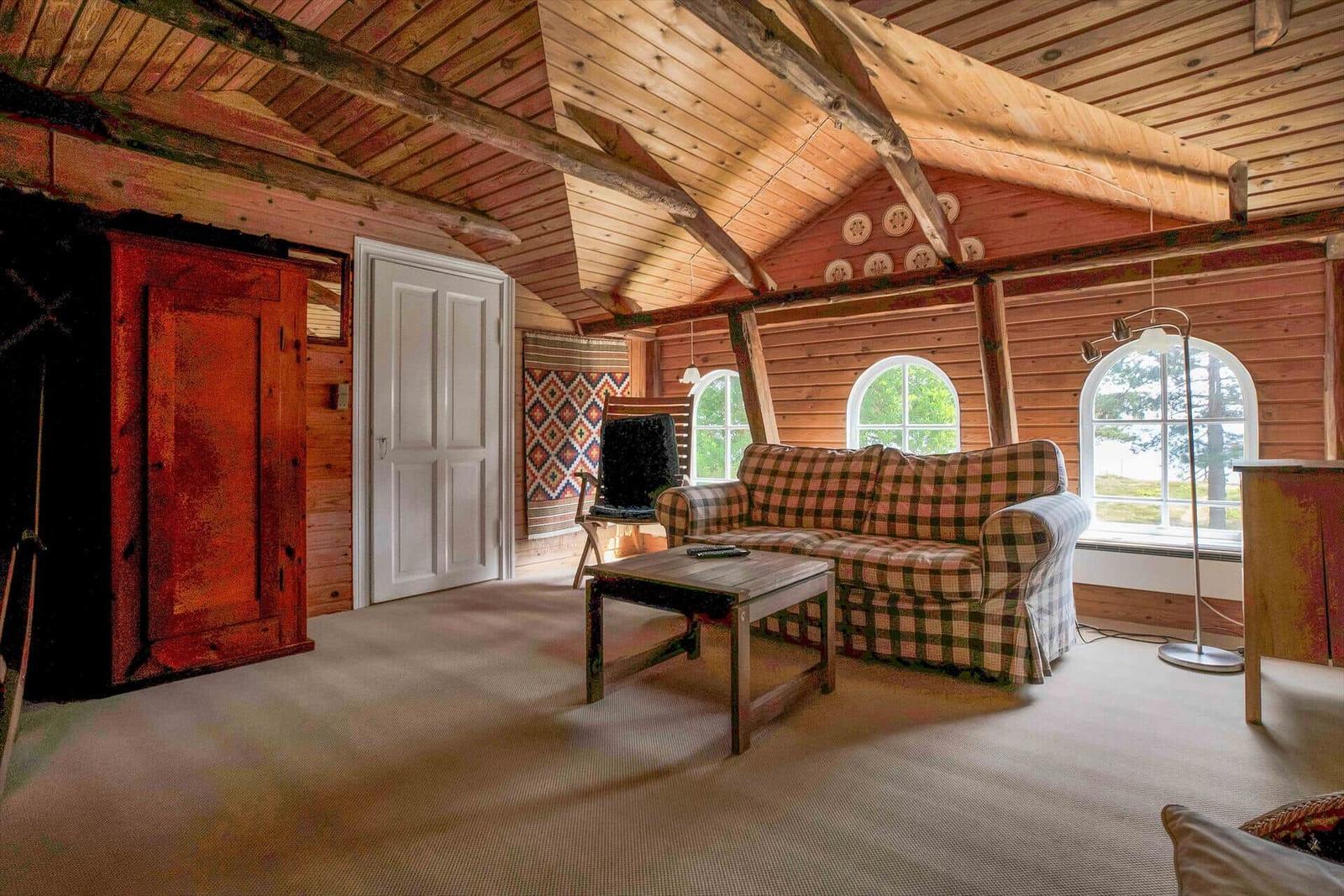 Schlafzimmer mit Doppelbett, zwei Fenstern, Holzdecke und Teppichboden.